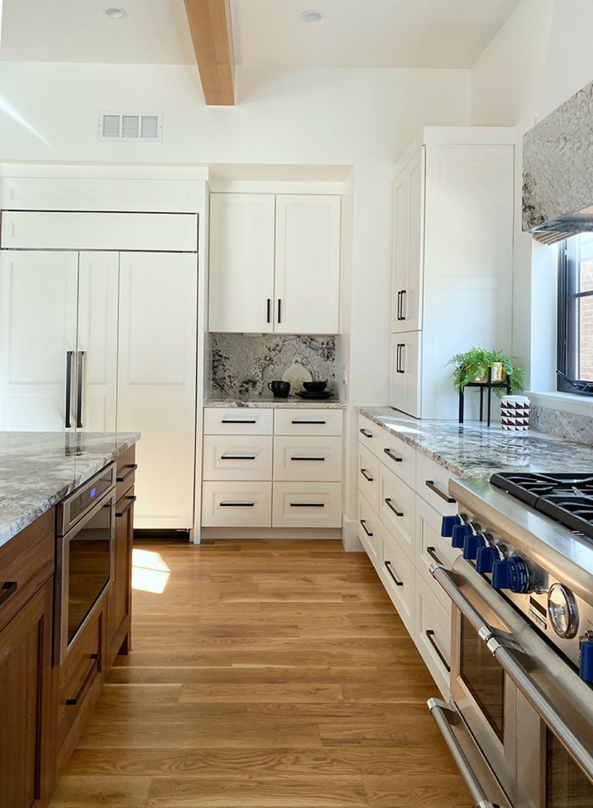 White cabinetry, natural stone, and a wood island in the Spengler Residence kitchen.